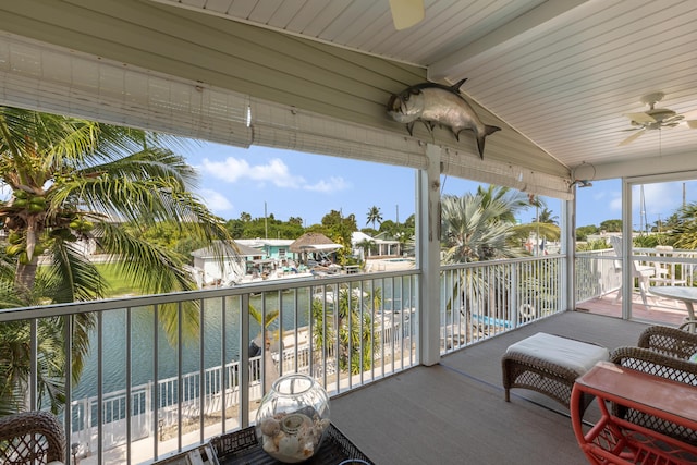 sunroom / solarium with lofted ceiling, ceiling fan, and a water view