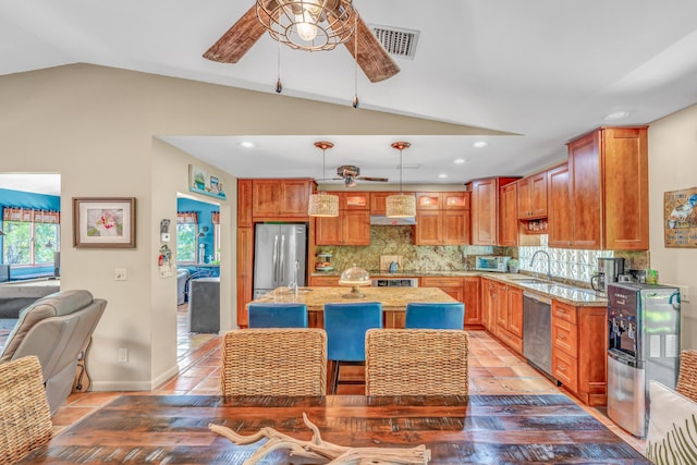 kitchen featuring visible vents, a ceiling fan, appliances with stainless steel finishes, wall chimney exhaust hood, and decorative backsplash