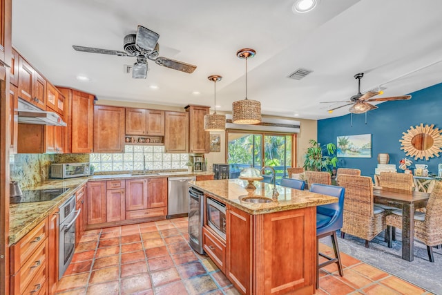 kitchen with tasteful backsplash, visible vents, appliances with stainless steel finishes, a kitchen breakfast bar, and a sink