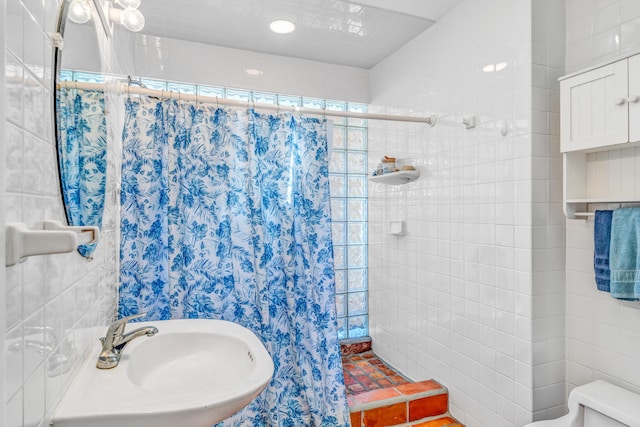 full bathroom with a sink, toilet, and tiled shower