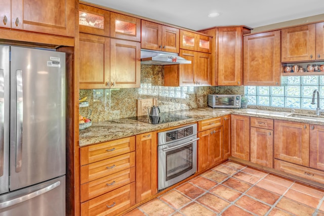 kitchen featuring a toaster, a sink, stainless steel appliances, under cabinet range hood, and backsplash