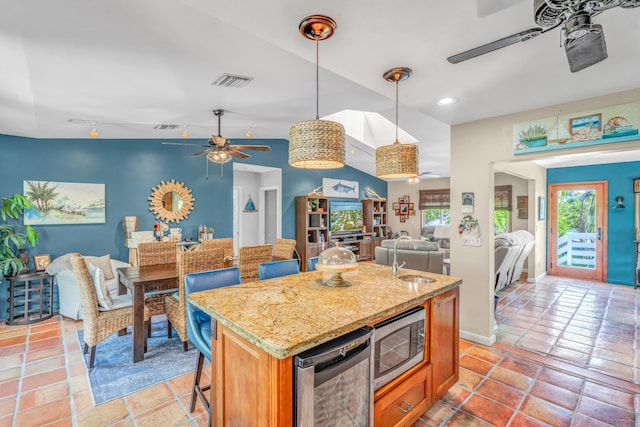 kitchen featuring open floor plan, ceiling fan, stainless steel microwave, and visible vents