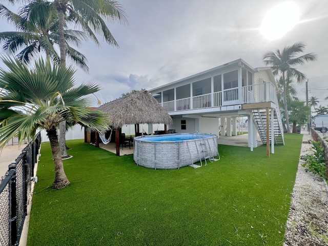 rear view of property featuring a sunroom, a patio area, and a lawn