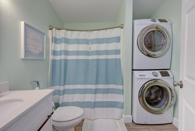 bathroom featuring toilet, vanity, stacked washing maching and dryer, and a shower with curtain