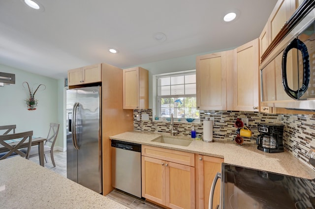 kitchen featuring sink, backsplash, stainless steel appliances, light stone counters, and light brown cabinets