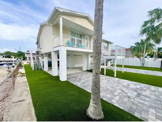 back of property with a carport, central AC unit, and a lawn