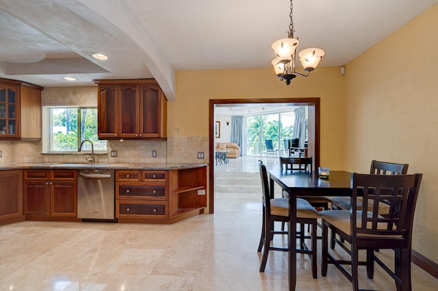 kitchen with sink, stainless steel dishwasher, pendant lighting, light stone countertops, and decorative backsplash