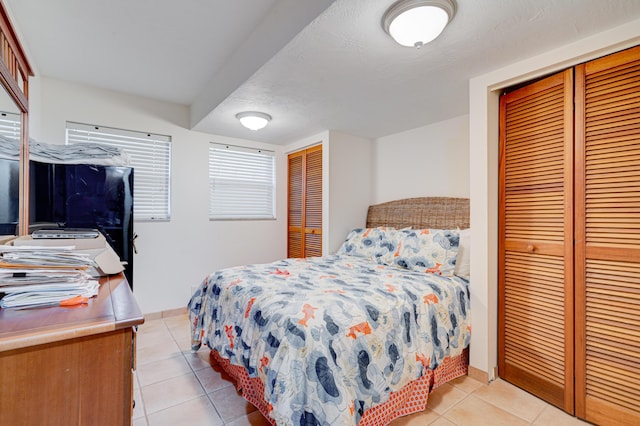 bedroom featuring light tile patterned flooring, a textured ceiling, and two closets