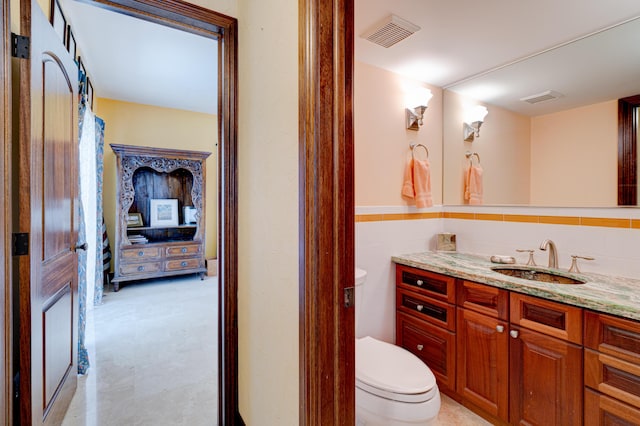 bathroom with vanity, tile walls, and toilet