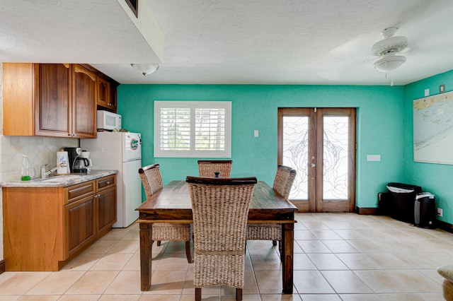 tiled dining area featuring french doors, ceiling fan, sink, and a textured ceiling