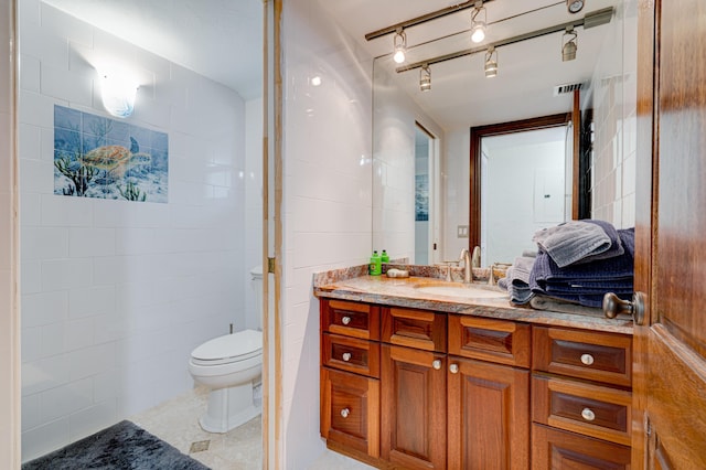 bathroom with vanity, tile patterned floors, tile walls, and toilet