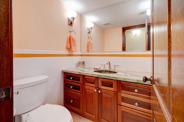 bathroom with tile walls, vanity, and toilet