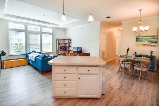 kitchen featuring a raised ceiling, white cabinetry, pendant lighting, and tile counters