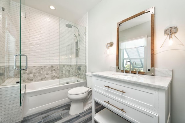 full bathroom featuring shower / bath combination with glass door, wood finished floors, toilet, and vanity