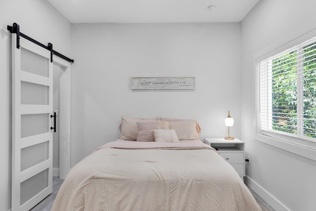 bedroom with hardwood / wood-style flooring and a barn door