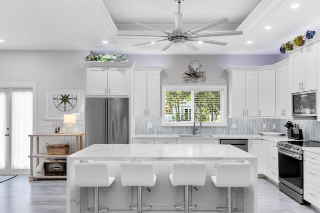 kitchen featuring appliances with stainless steel finishes, a center island, sink, and white cabinets