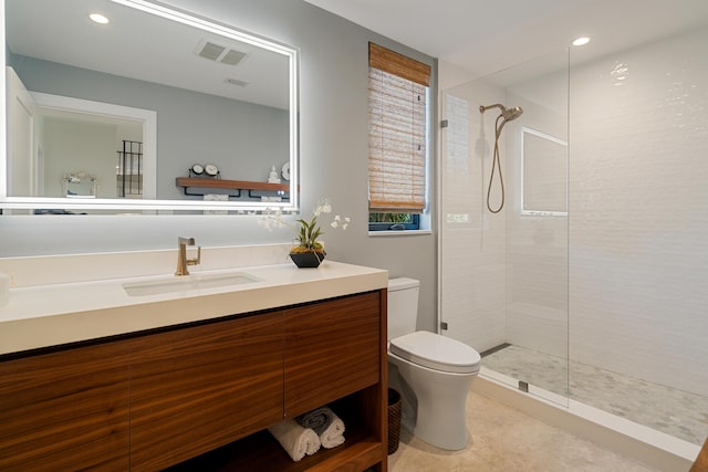 bathroom featuring vanity, a tile shower, and toilet