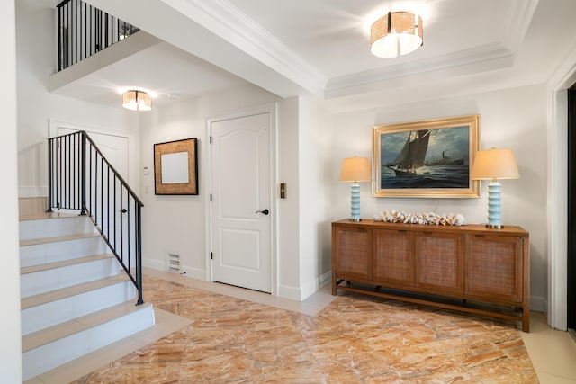 entryway featuring a tray ceiling and crown molding