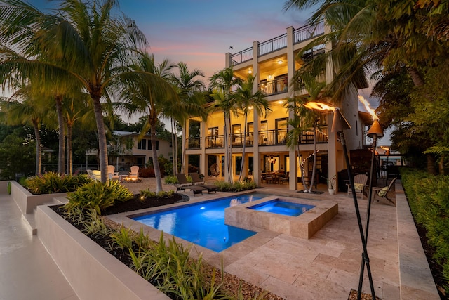 pool at dusk featuring an in ground hot tub, a fire pit, and a patio area