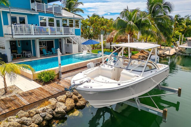 view of pool featuring a water view, a patio, and a boat dock