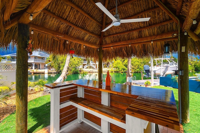 view of patio with a bar, a gazebo, ceiling fan, and a water view