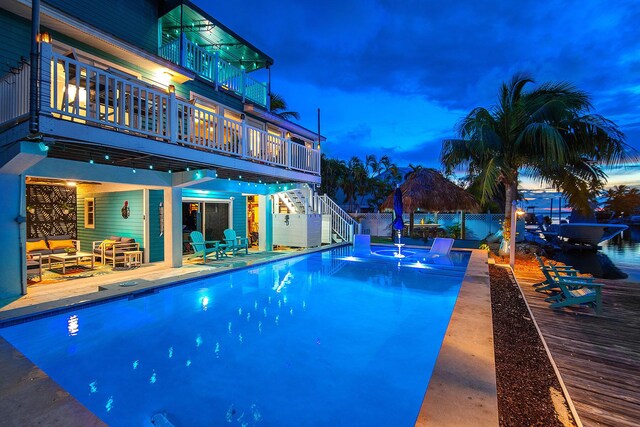 pool at dusk featuring a wooden deck, a jacuzzi, a patio area, and outdoor lounge area