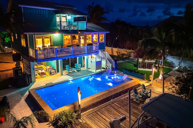 pool at twilight with an in ground hot tub and a wooden deck