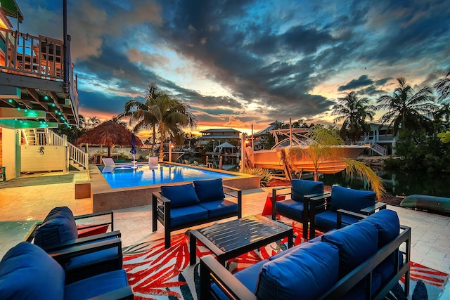 pool at dusk with outdoor lounge area and a patio