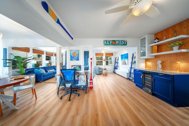 interior space featuring blue cabinets, white cabinetry, beverage cooler, light stone countertops, and light wood-type flooring