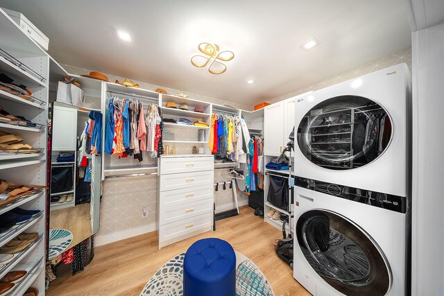 laundry area featuring stacked washer and clothes dryer and light hardwood / wood-style flooring