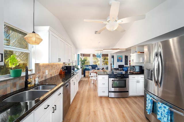 kitchen with sink, vaulted ceiling, hanging light fixtures, stainless steel appliances, and white cabinets