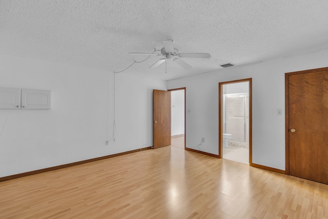 unfurnished bedroom featuring light wood finished floors, baseboards, visible vents, connected bathroom, and a textured ceiling