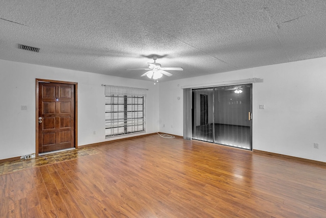 spare room with a ceiling fan, visible vents, baseboards, and wood finished floors