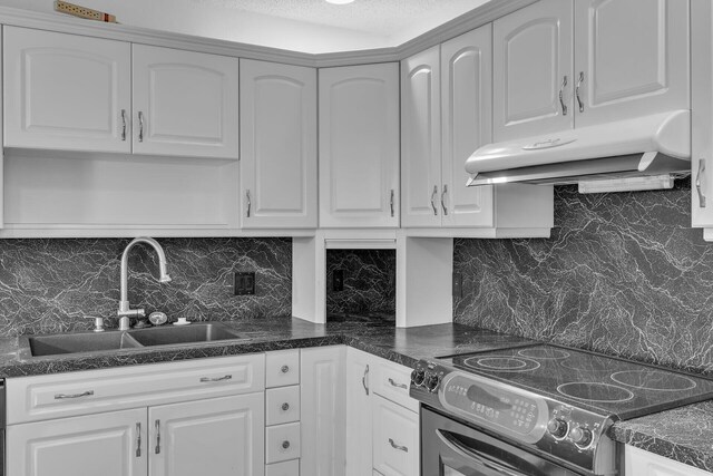 kitchen featuring dark countertops, under cabinet range hood, electric range, and white cabinets