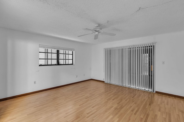 empty room with ceiling fan, a textured ceiling, baseboards, and wood finished floors