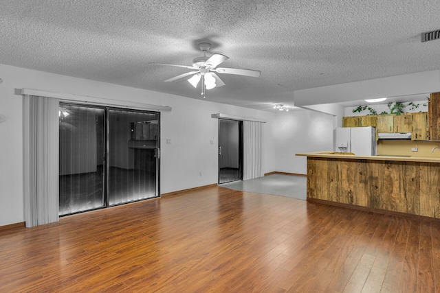 unfurnished living room featuring visible vents, ceiling fan, a textured ceiling, and wood finished floors