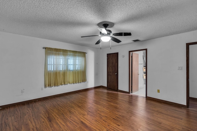 empty room featuring baseboards, visible vents, a ceiling fan, wood finished floors, and a textured ceiling