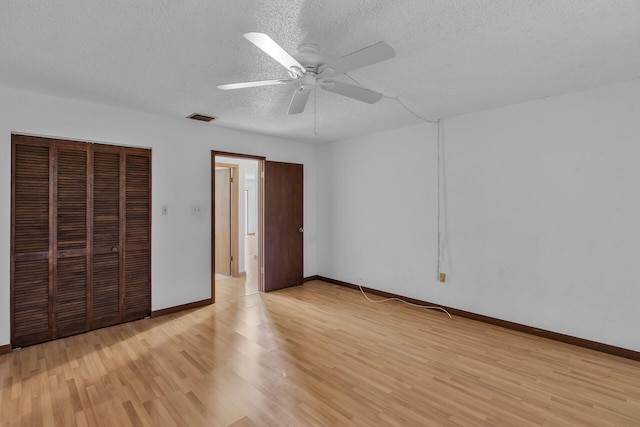 unfurnished bedroom featuring light wood finished floors, a closet, visible vents, and a textured ceiling