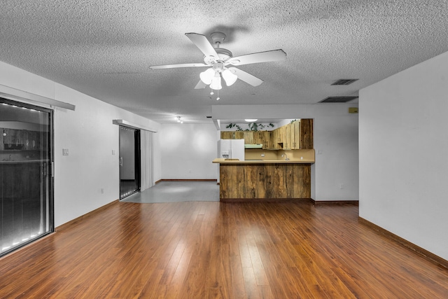 unfurnished living room with dark wood-style floors, ceiling fan, a textured ceiling, and visible vents