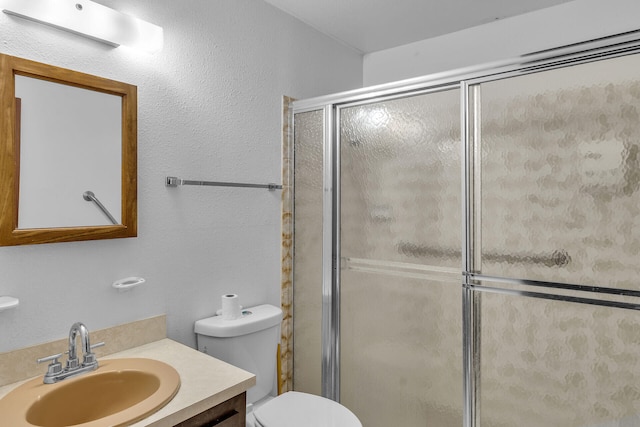 bathroom with a textured wall, vanity, toilet, and an enclosed shower