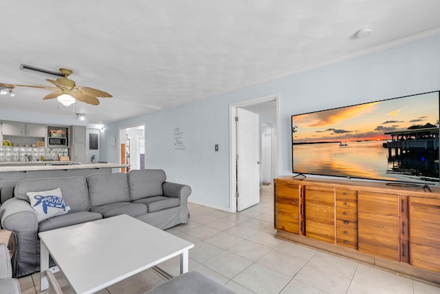 living area with light tile patterned floors, ceiling fan, baseboards, and crown molding