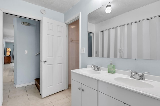 bathroom with double vanity, a sink, a textured ceiling, and tile patterned floors