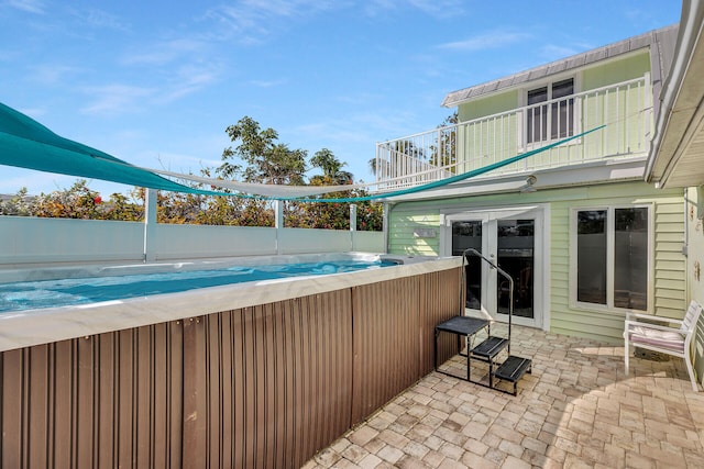 view of patio / terrace with a pool, fence, and a balcony