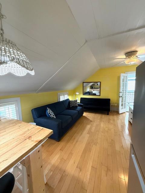 additional living space featuring lofted ceiling, a wealth of natural light, light wood-style floors, and a ceiling fan