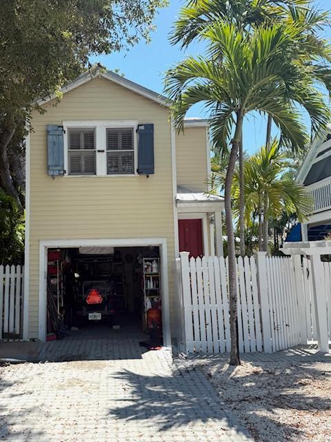 view of front of property featuring driveway, a garage, and fence