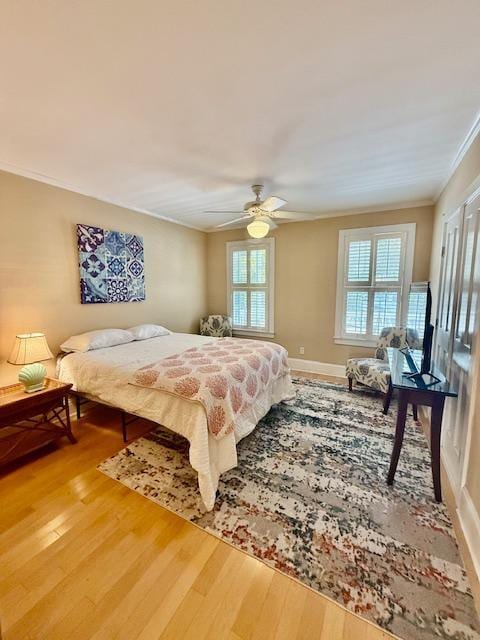 bedroom with ornamental molding, light wood-style flooring, baseboards, and ceiling fan