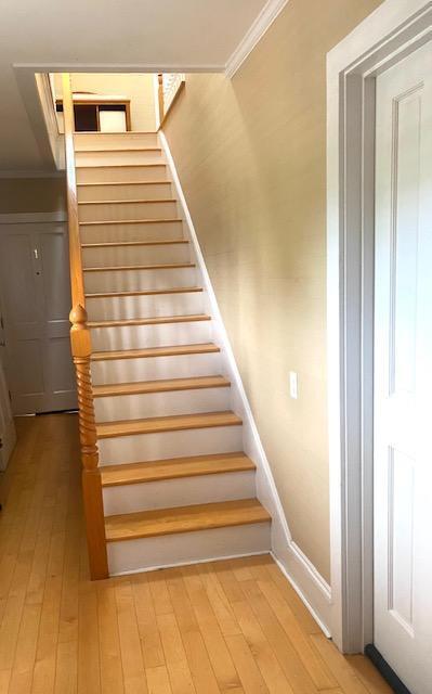 staircase featuring ornamental molding and hardwood / wood-style floors