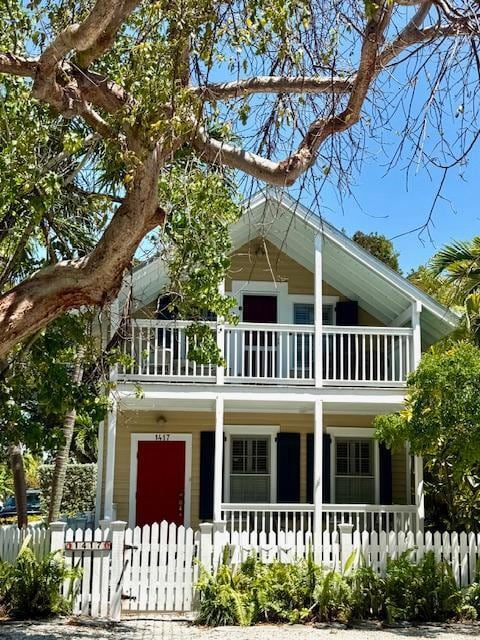 view of front of house featuring a balcony, a fenced front yard, and covered porch