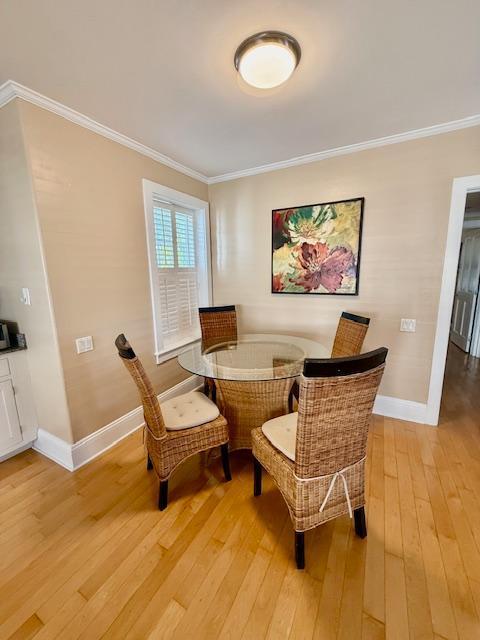 dining space with light wood-style floors, baseboards, and ornamental molding