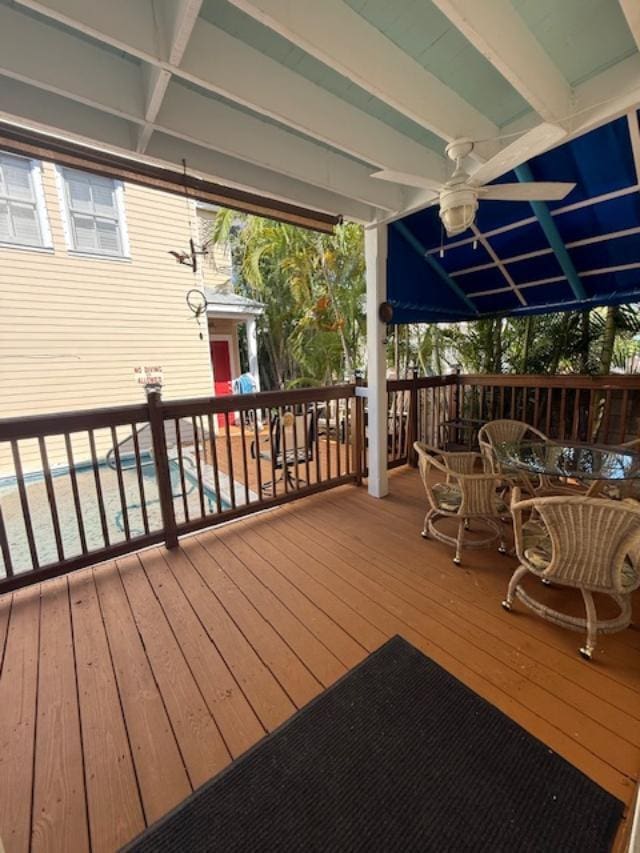 wooden terrace with a ceiling fan, outdoor dining area, and a pool